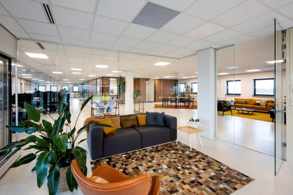 Modern ingerichte kantoorruimte aan de Joop Geesinkweg met loungehoek, vergadertafels en glazen wanden.