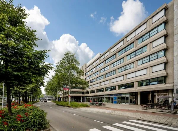 Straatbeeld van Westblaak in Rotterdam met een modern kantoorgebouw, groenstrook en fietsenstalling.