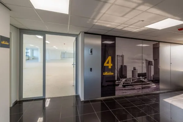 Ingang naar een lege kantoorruimte op de vierde verdieping van een modern kantoorgebouw aan de Westblaak, met een wandfoto van de Rotterdamse skyline.