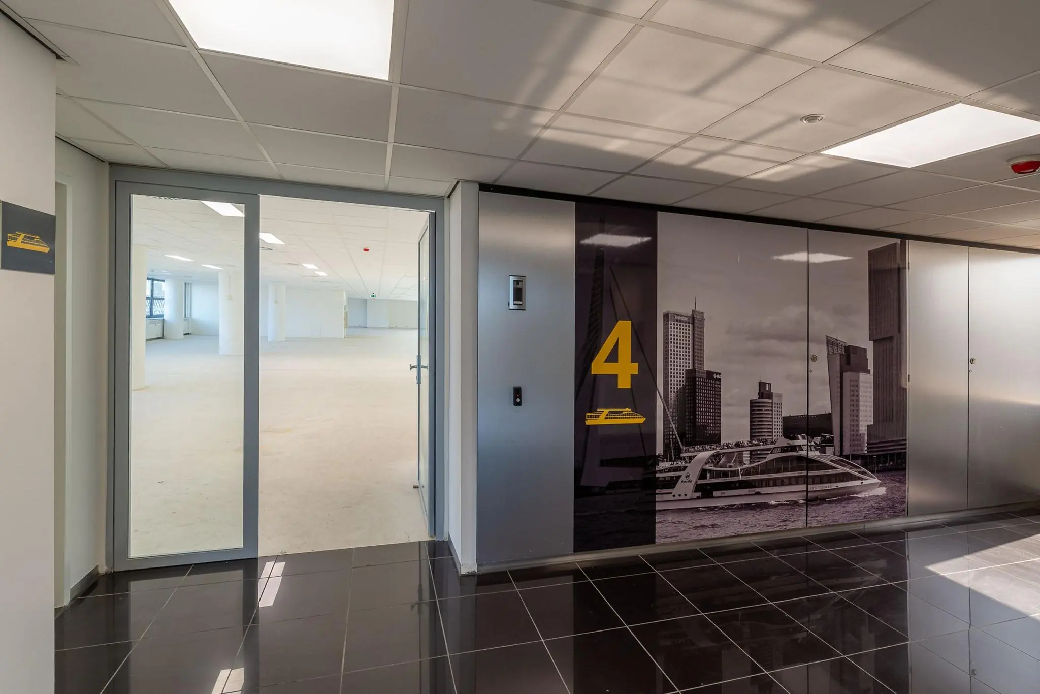 Ingang naar een lege kantoorruimte op de vierde verdieping van een modern kantoorgebouw aan de Westblaak, met een wandfoto van de Rotterdamse skyline.