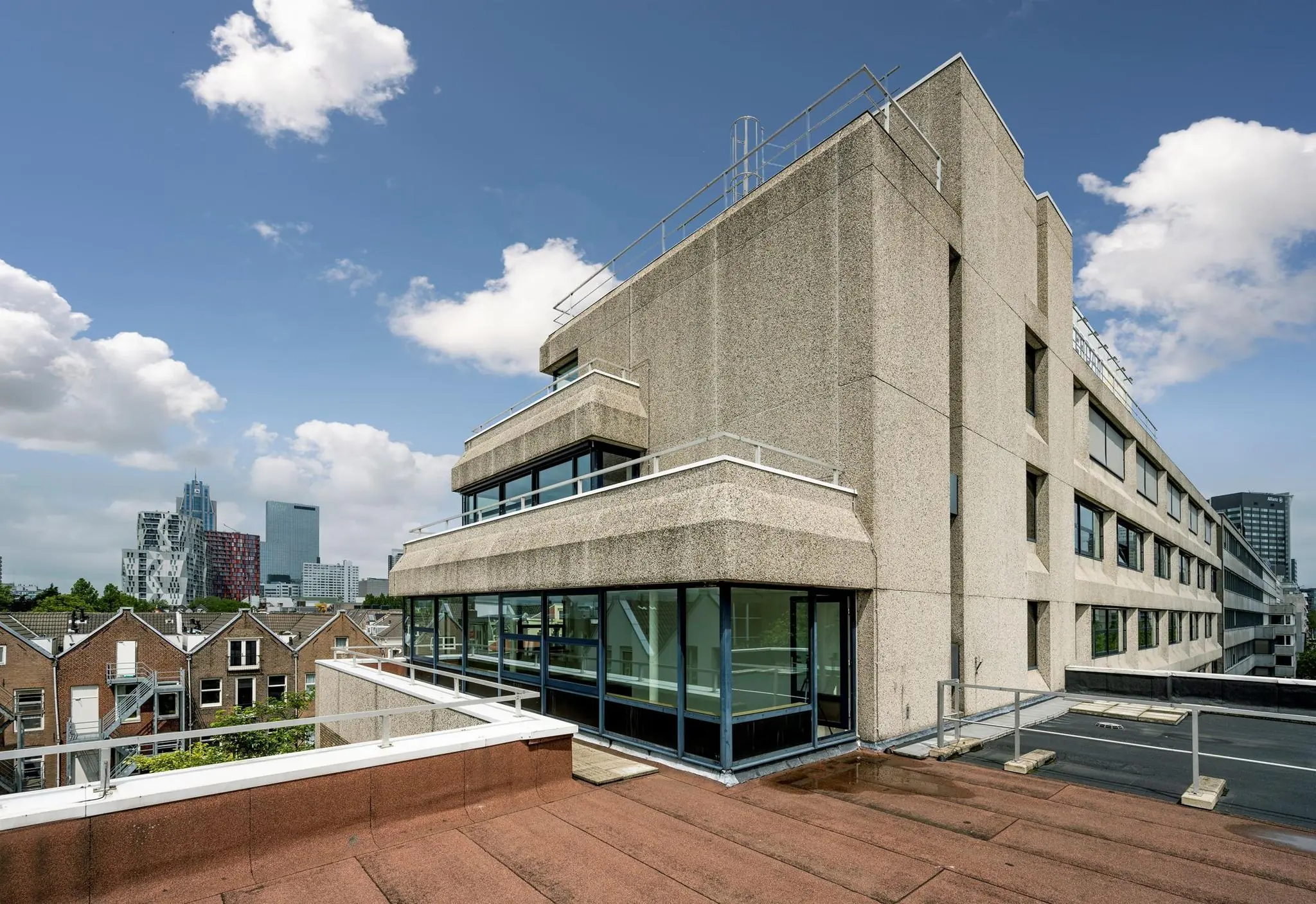 Brutalistisch kantoorgebouw aan de Westblaak in Rotterdam met uitzicht op moderne hoogbouw en traditionele woningen.