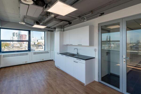 Moderne kantoorruimte aan de Westblaak met pantry, houten vloer en uitzicht op de skyline van Rotterdam.