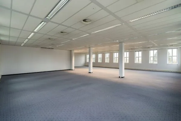 Lege kantoorruimte aan de Vareseweg met systeemplafond, tapijtvloer en grote ramen.