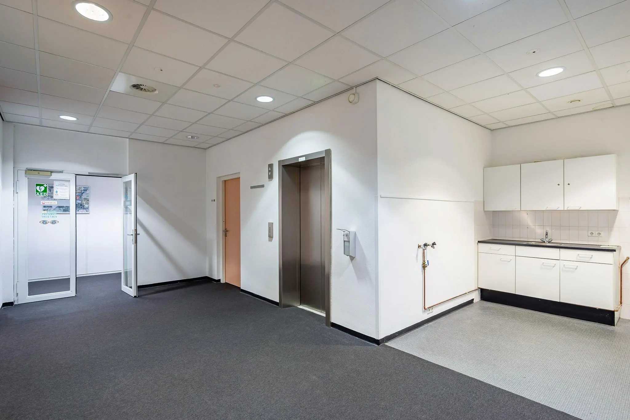 Hal met lift, pantry en deuren in een kantoorpand aan de Vareseweg.