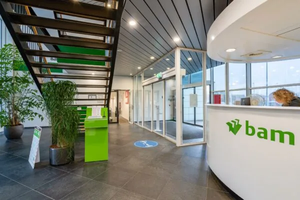 Moderne ontvangsthal van BAM aan de Vareseweg met balie, trap en glazen entree.