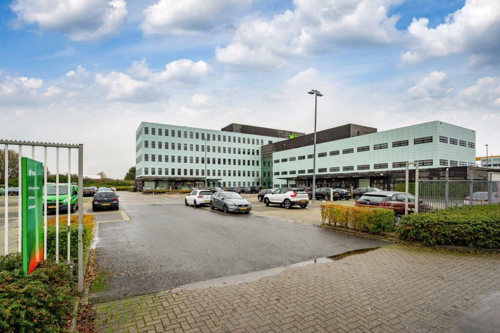 Modern kantoorgebouw aan de Vareseweg in Rotterdam met parkeerplaats op de voorgrond.