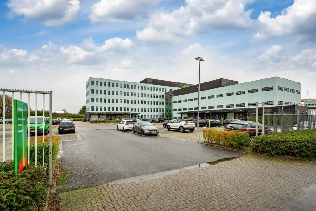 Modern kantoorgebouw aan de Vareseweg in Rotterdam met parkeerplaats op de voorgrond.