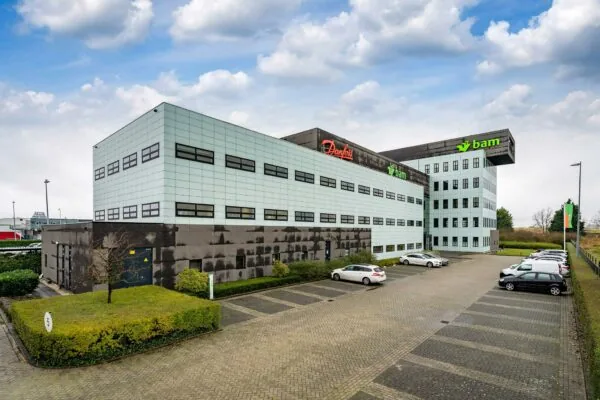 Kantoorpand aan de Vareseweg met de logo’s van Danfoss en BAM op de gevel en een parkeerterrein op de voorgrond.
