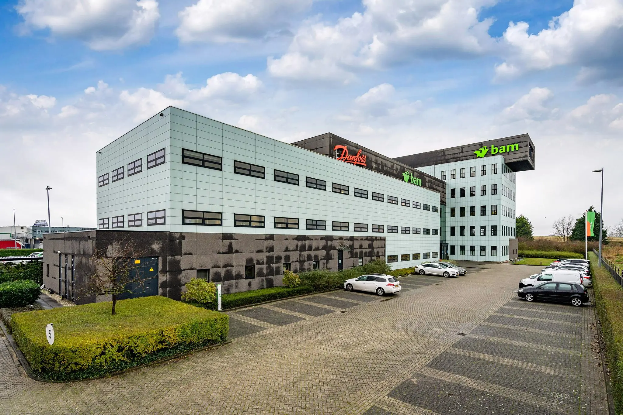 Kantoorpand aan de Vareseweg met de logo’s van Danfoss en BAM op de gevel en een parkeerterrein op de voorgrond.