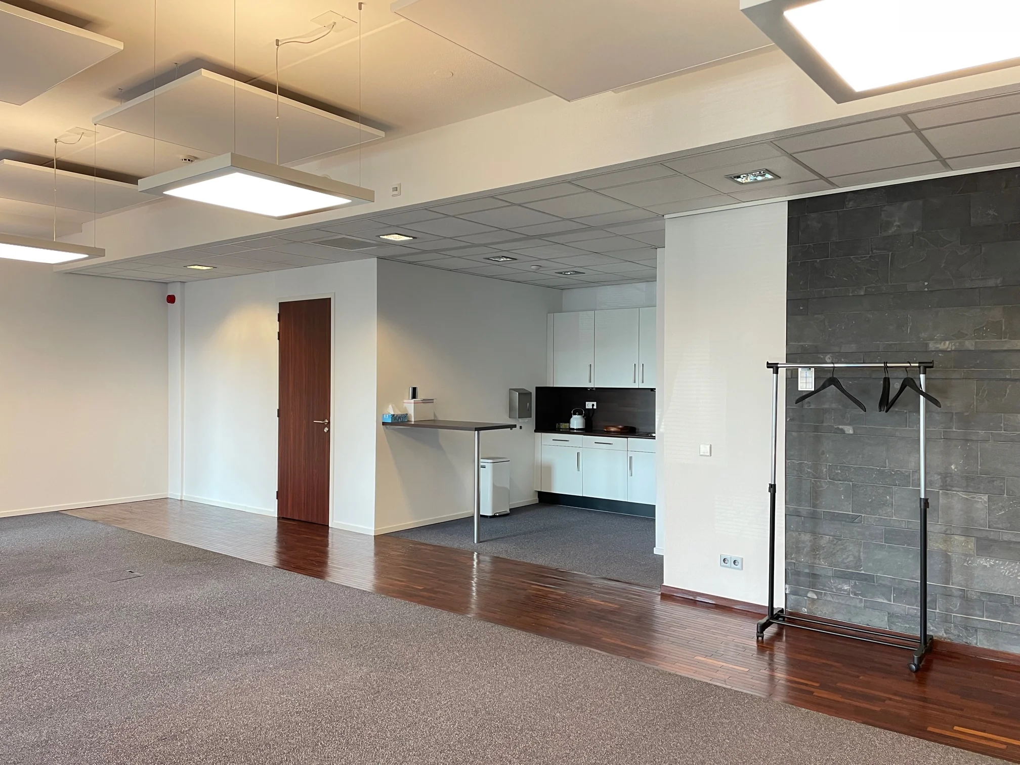 Moderne kantoorruimte aan de Linatebaan met open keuken, donkerhouten vloer en kapstok.