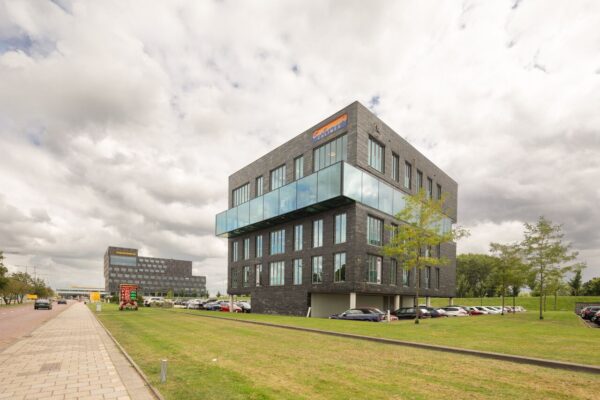 Modern kantoorgebouw aan de Linatebaan met glazen uitbouw en parkeerplaatsen op de voorgrond.
