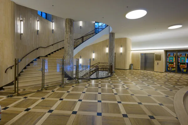 Ruime en stijlvolle hal van het stadhuis aan de Coolsingel met een marmeren trap, lift en kunstwerken naast de ingang.