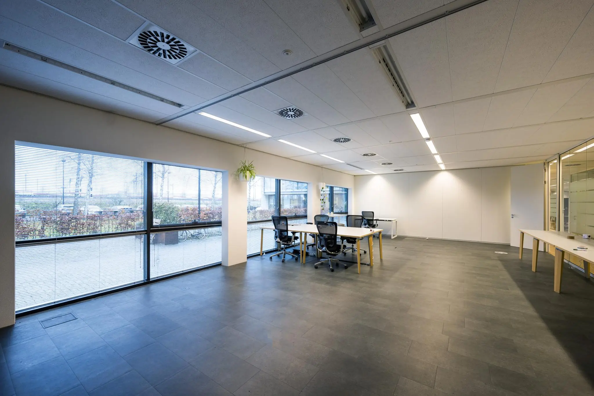 Moderne, lichte kantoorruimte aan de Naritaweg met werkplekken en grote ramen met uitzicht naar buiten.