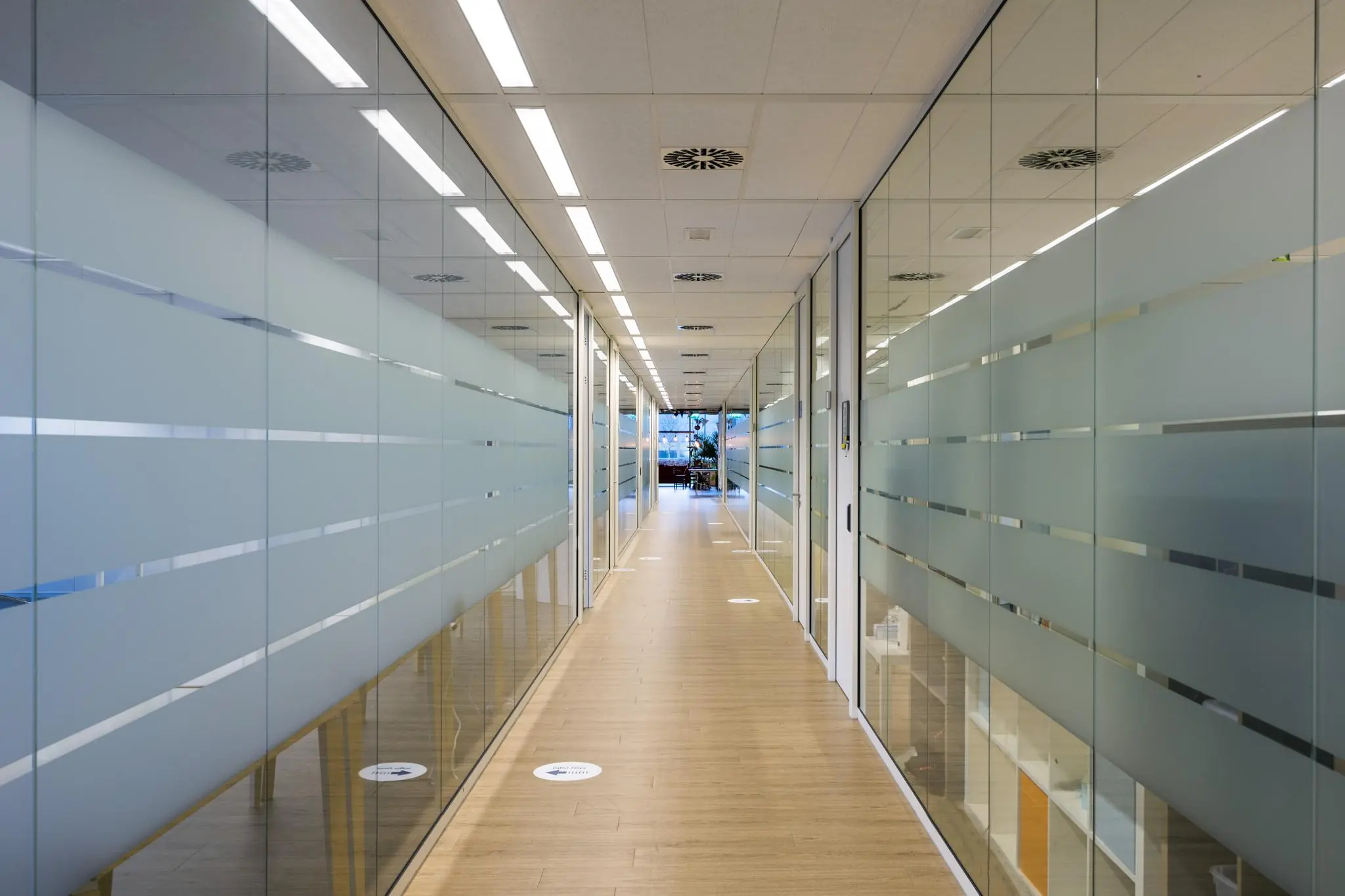 Gang in een modern kantoorgebouw aan de Naritaweg met glazen wanden en houten vloer.