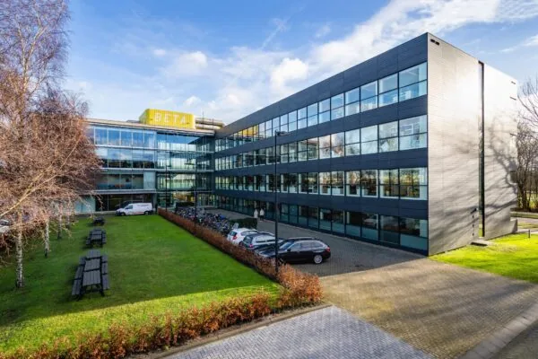 Kantoorgebouw aan de Naritaweg in Amsterdam met moderne gevel, parkeerplaatsen en groenvoorziening.
