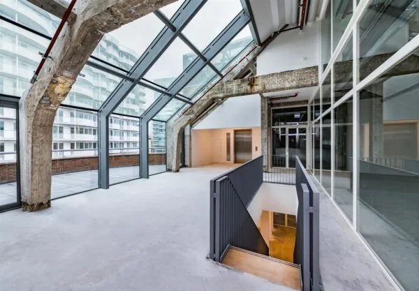 Industriële loft aan de Coolsingel met glazen gevel, betonnen draagconstructie en toegang tot dakterras.