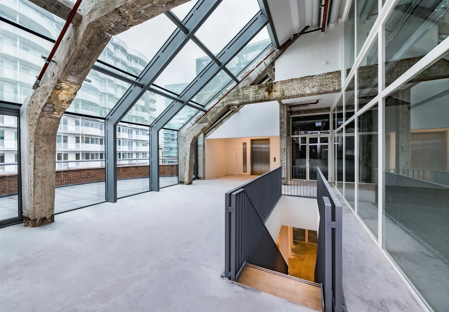 Industriële loft aan de Coolsingel met glazen gevel, betonnen draagconstructie en toegang tot dakterras.
