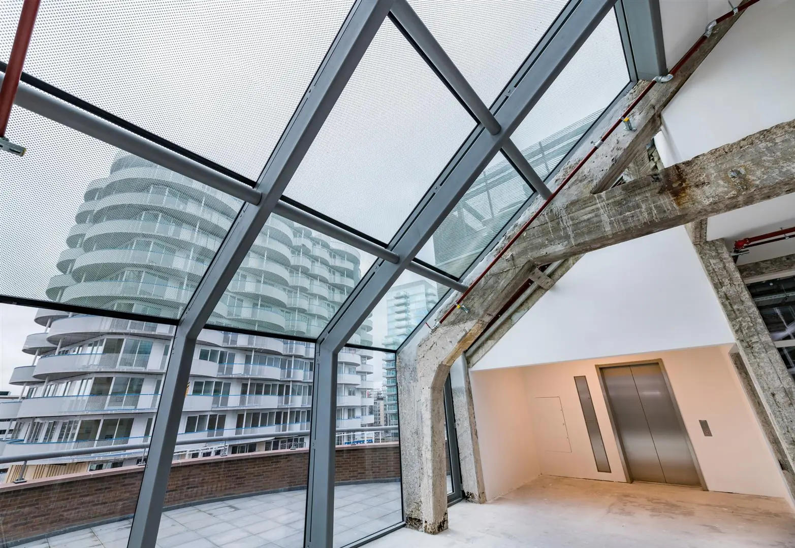 Uitzicht vanuit een modern gerenoveerd gebouw aan de Coolsingel met zicht op omliggende appartementencomplexen door een glazen gevel.