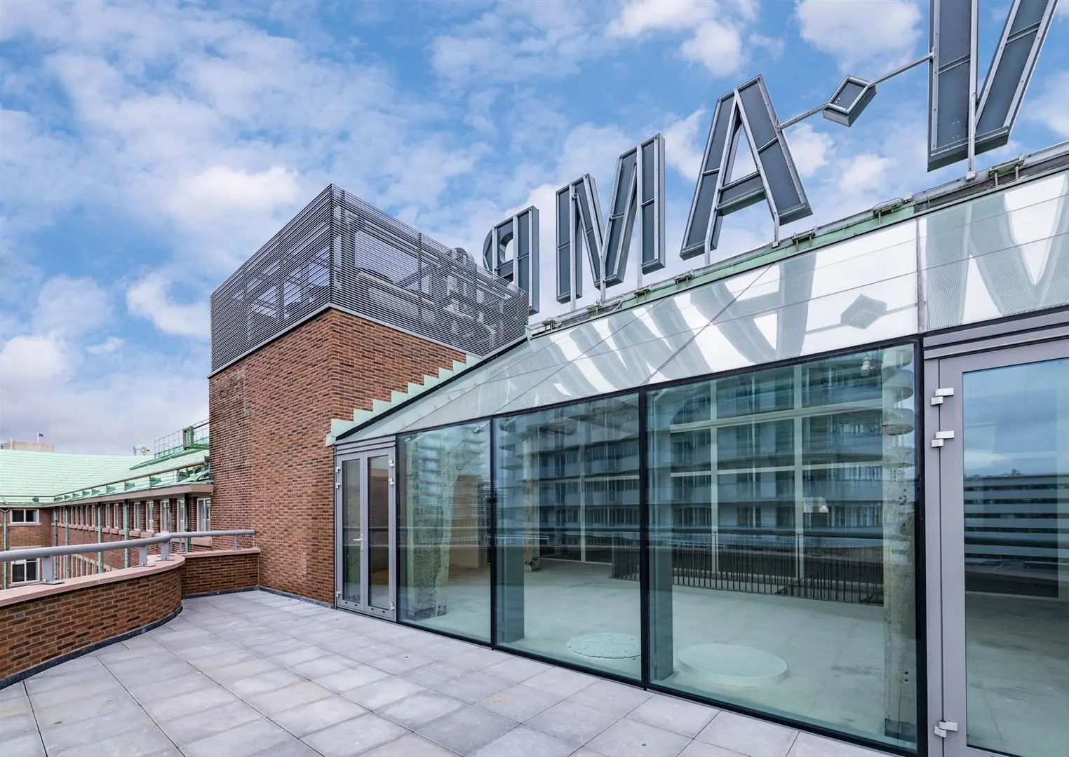 Glazen gevel en dakterras van een modern gebouw aan de Coolsingel in Rotterdam met zicht op omliggende architectuur.
