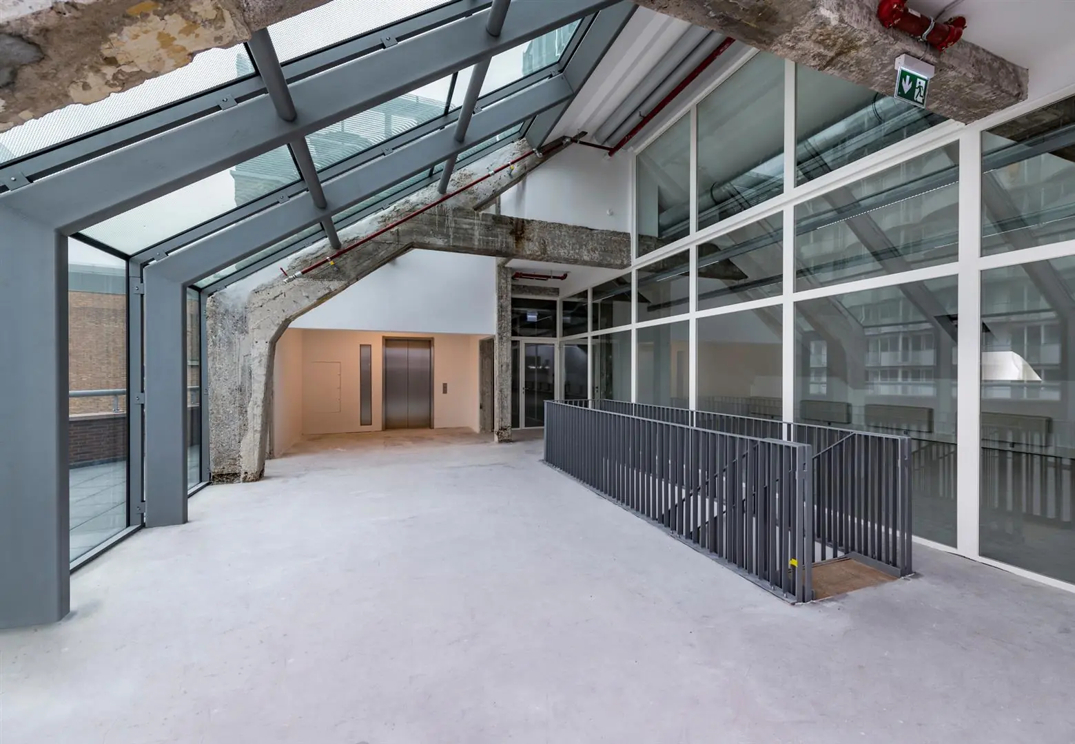 Moderne, industriële binnenruimte aan de Coolsingel met lift, glazen gevel en betonnen details.