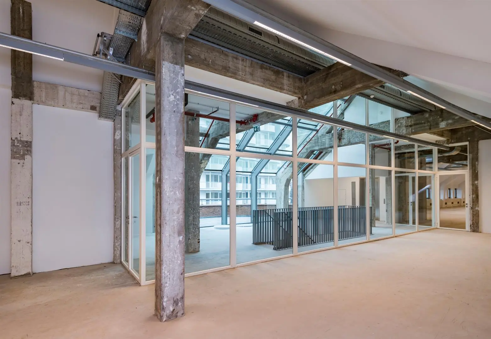 Industrieel ogende kantoorruimte aan de Coolsingel met betonnen kolommen, glazen wanden en grote raampartijen.