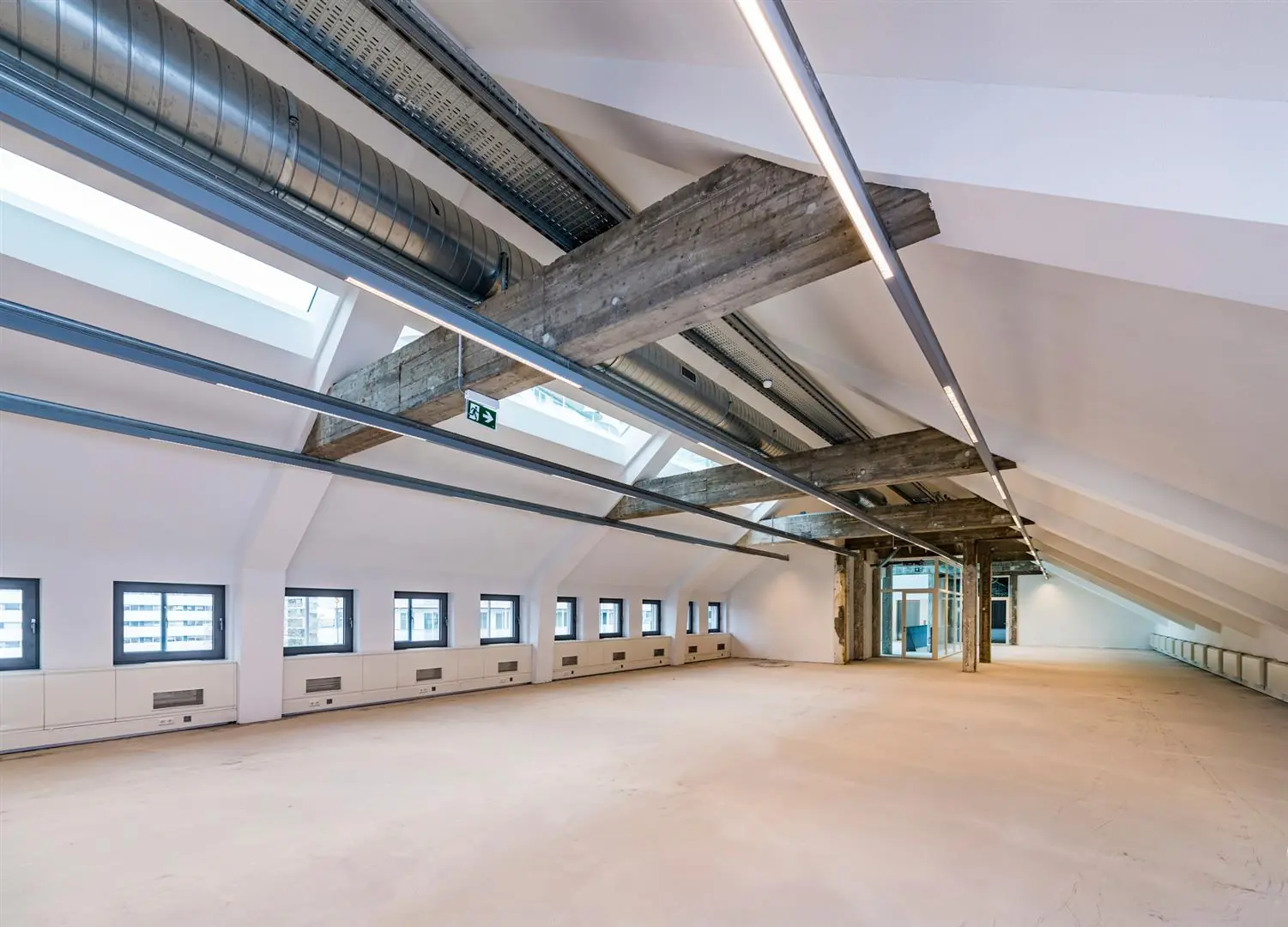 Leeg, industrieel ogend zolderkantoor aan de Coolsingel met zichtbare betonnen balken, ventilatiebuizen en dakramen.