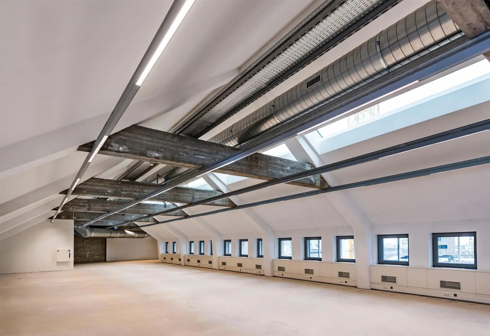 Licht en modern ingericht leeg kantoor op de bovenste verdieping aan de Coolsingel met zichtbare ventilatiebuizen en houten draagbalken.