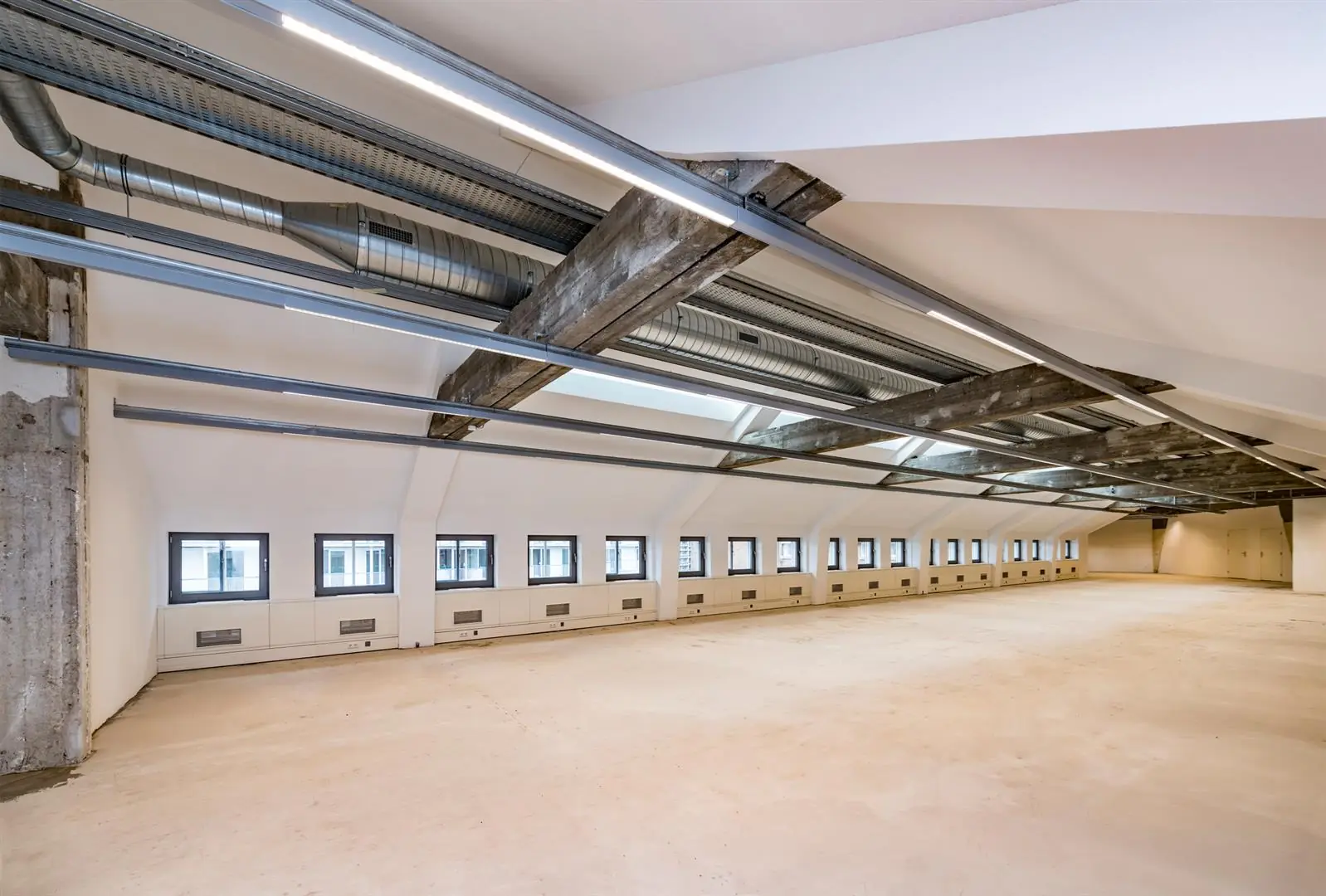 Leeg kantoor- of bedrijfsruimte op de Coolsingel met een industriële uitstraling, zichtbare ventilatiebuizen en een rij kleine ramen.