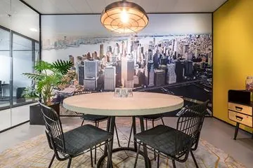 Moderne vergaderruimte op Wilhelminaplein met ronde tafel, vier stoelen en een muurvullende foto van de skyline van New York.