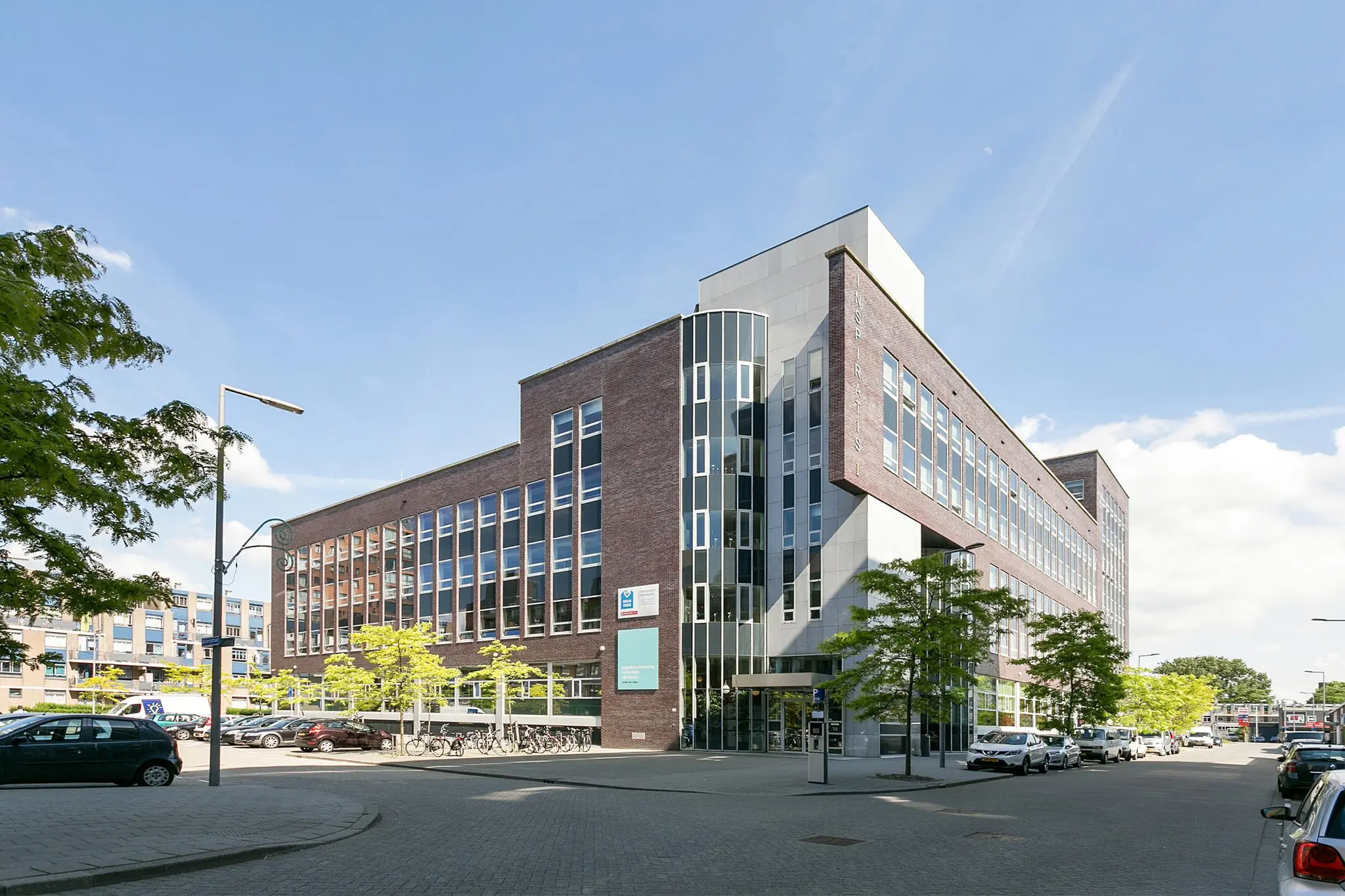 Modern kantoorgebouw aan de Dynamostraat in een stedelijke omgeving met geparkeerde auto's en fietsen.