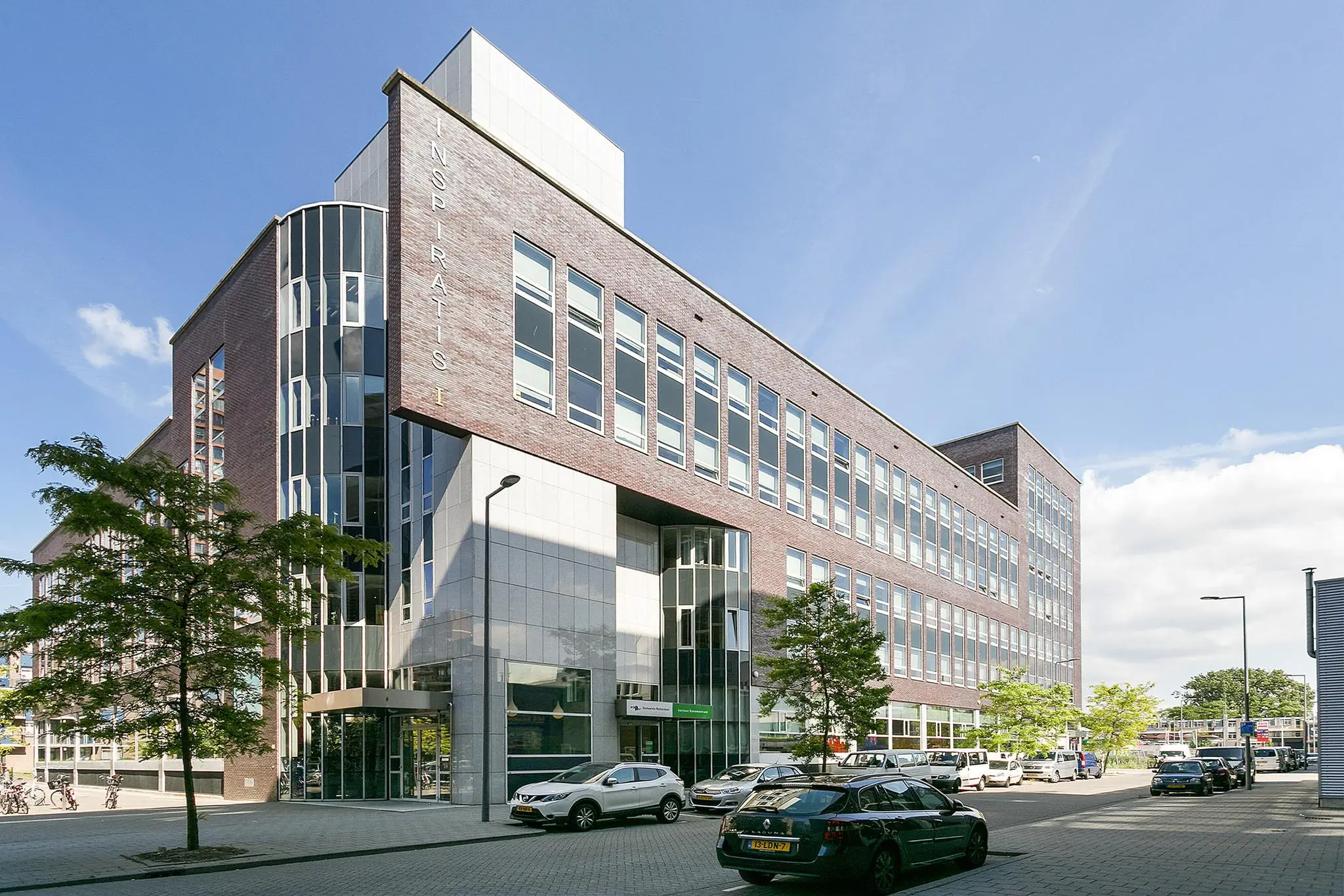 Modern kantoorgebouw aan de Dynamostraat met gevelbelettering “Inspiratis” en geparkeerde auto's langs de straat.