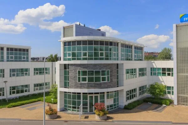 Modern kantoorgebouw aan het Rhijnspoor met witte gevel en grote raampartijen onder een blauwe lucht.