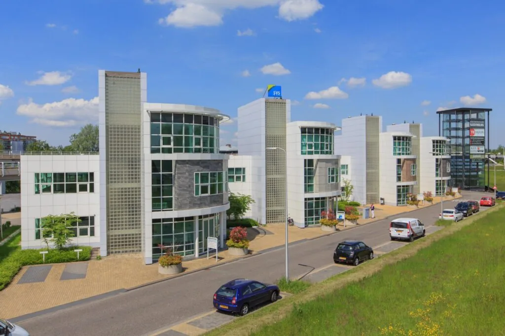 Moderne kantoorgebouwen aan het Rhijnspoor met glazen gevels en een helderblauwe lucht op de achtergrond.