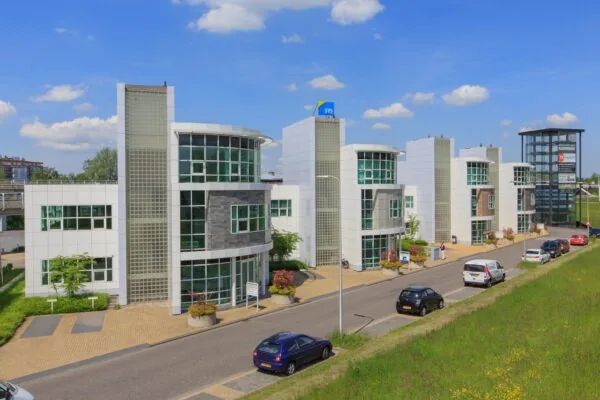 Moderne kantoorgebouwen aan het Rhijnspoor met glazen gevels en een helderblauwe lucht op de achtergrond.