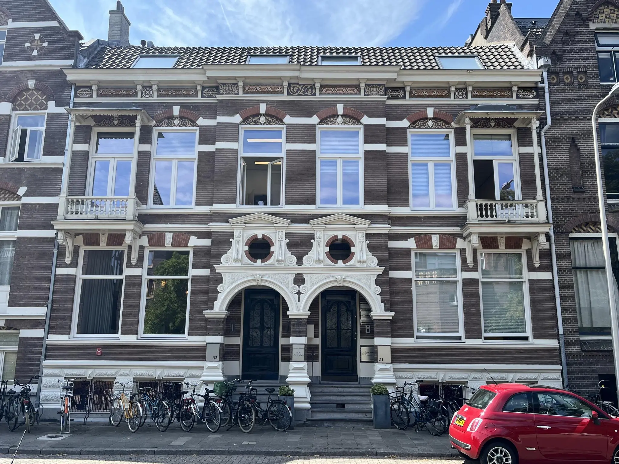 Voorgevel van een monumentaal herenhuis aan de Ramstraat met symmetrische architectuur, witte sierlijsten en meerdere geparkeerde fietsen ervoor.