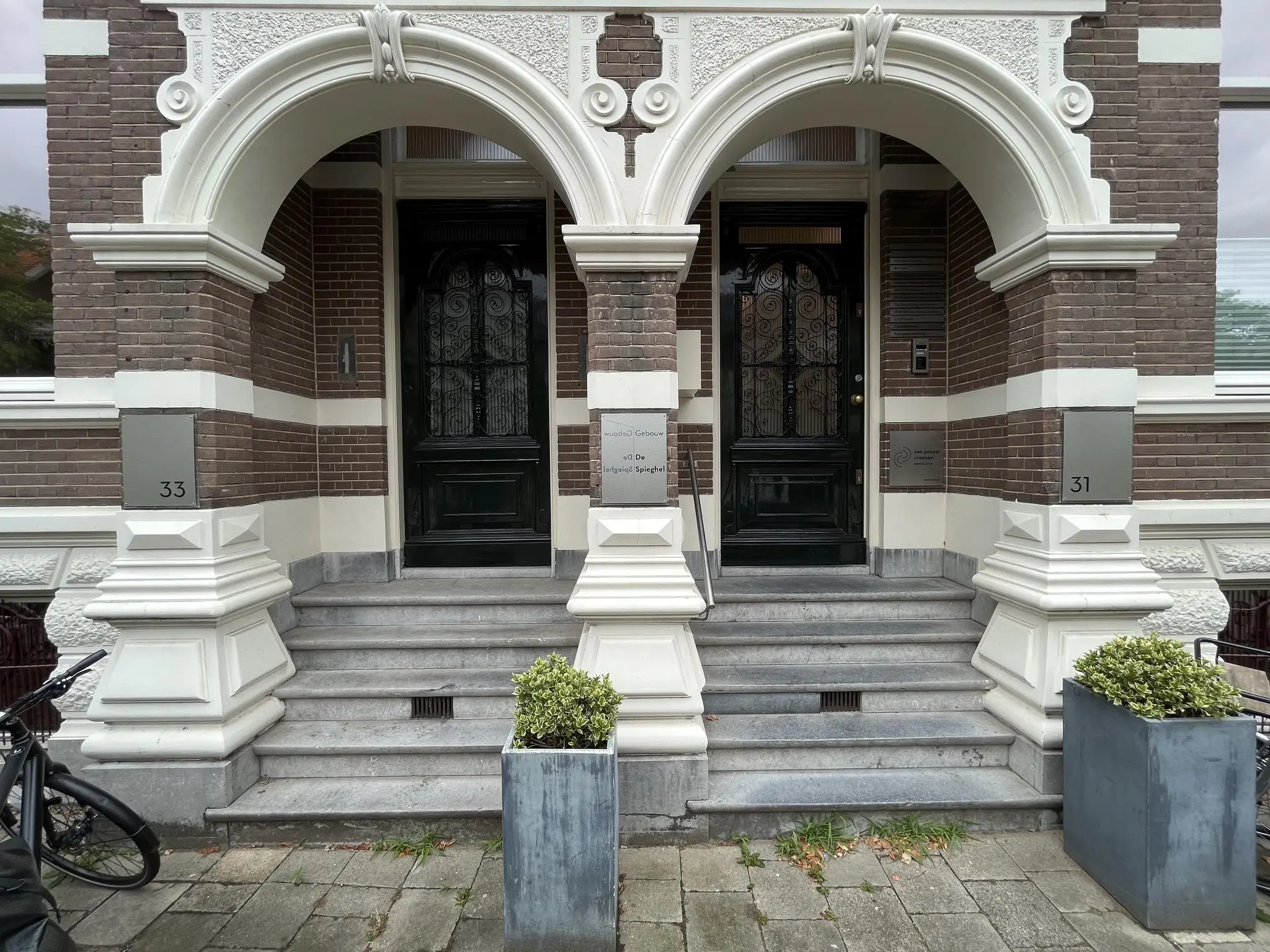 Twee identieke historische entrees met bogen en trappen van panden aan de Ramstraat, genummerd 31 en 33.