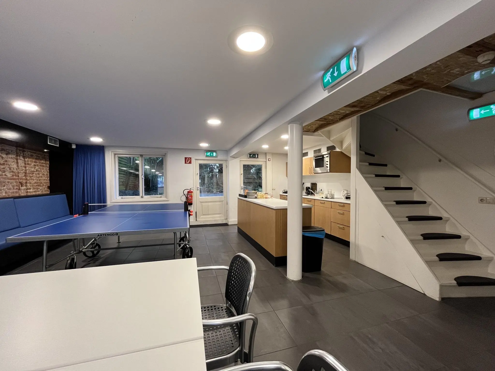 Gemeenschappelijke ruimte aan de Ramstraat met een tafeltennistafel, keuken en trap naar boven.