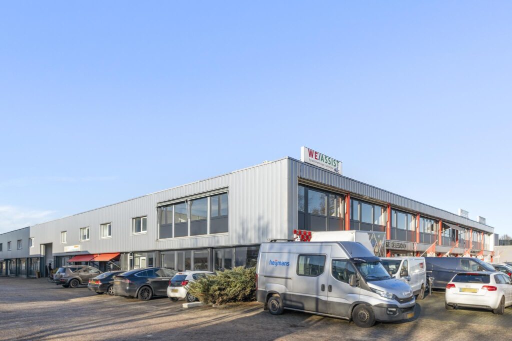 Bedrijfsverzamelgebouw aan de Nijverheidsweg met geparkeerde auto's en bestelbussen op de voorgrond.