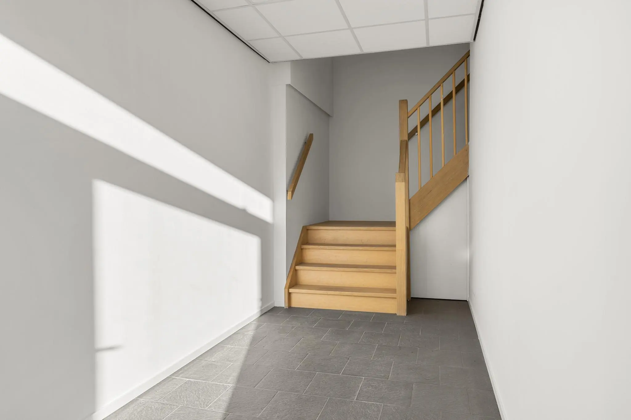 Houten trap in een lichtgrijze hal met tegelvloer aan de Nijverheidsweg.