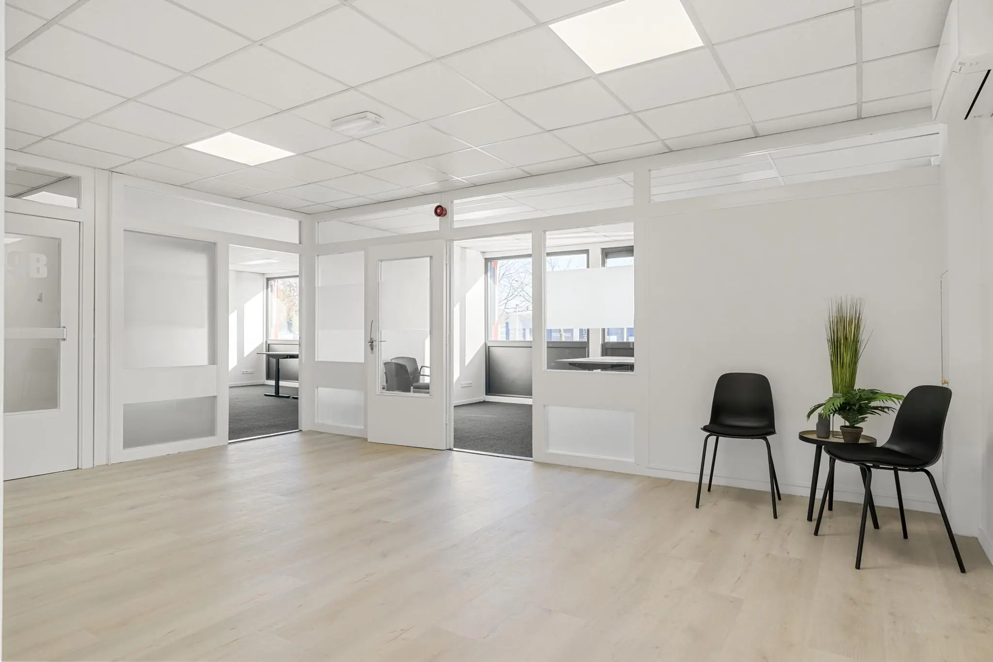 Moderne, lichte kantoorruimte aan de Nijverheidsweg met glazen tussenwanden, wachtruimte en bureaus in aparte kamers.