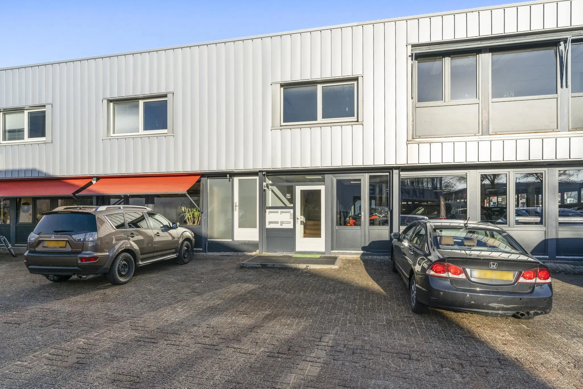 Bedrijfspand aan de Nijverheidsweg met twee geparkeerde auto's op de oprit.