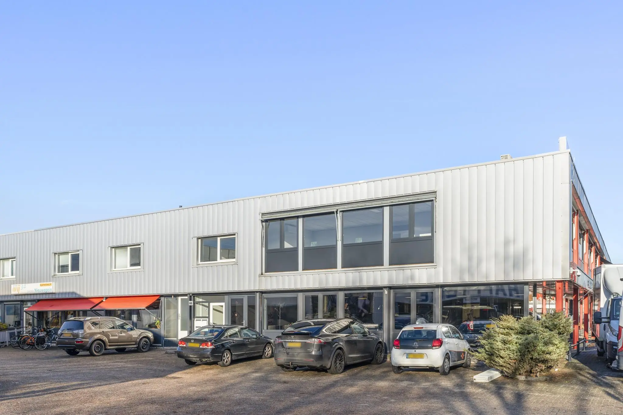 Bedrijfsgebouw aan de Nijverheidsweg met geparkeerde auto's op de voorgrond.