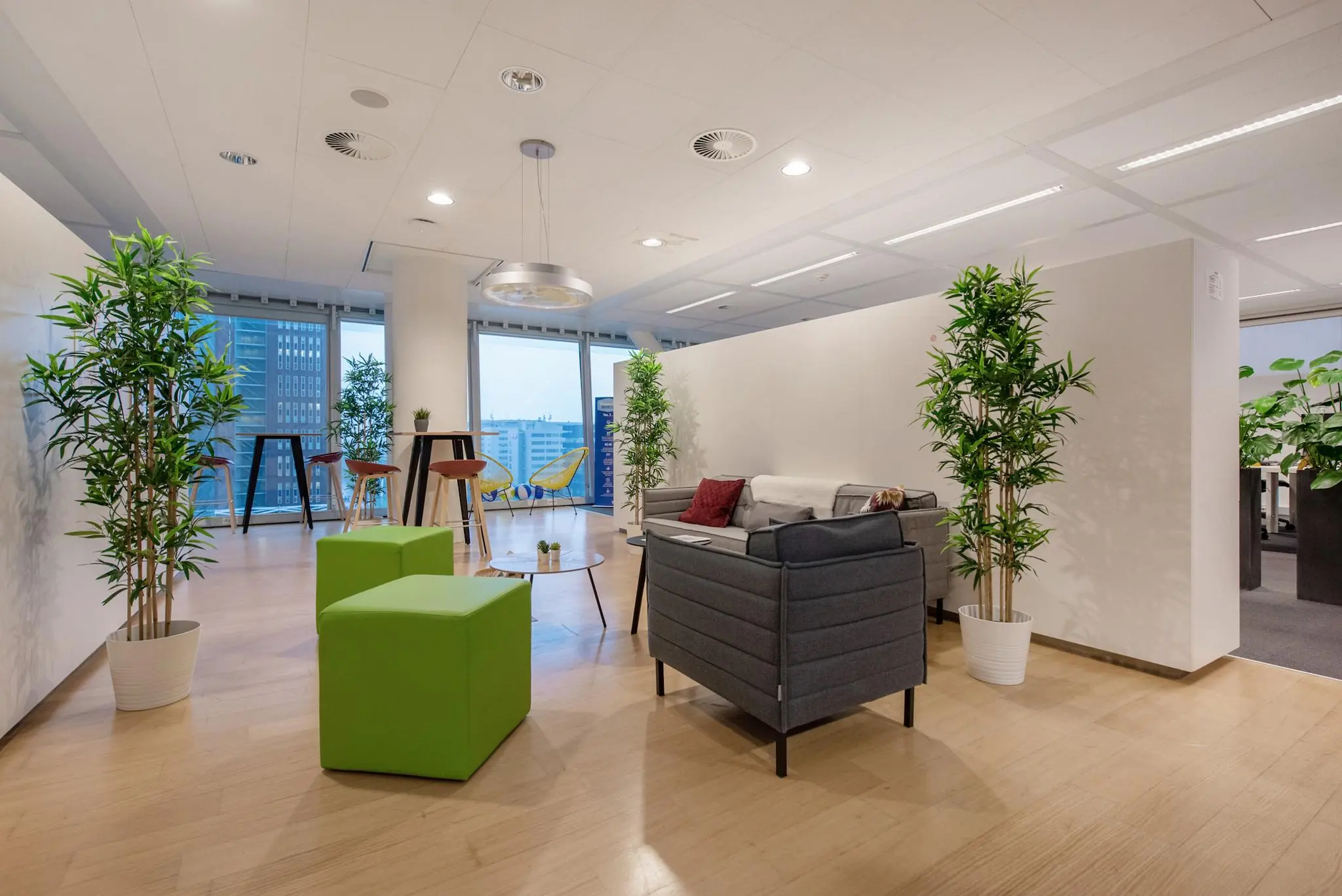 Moderne en open kantoorlounge aan de Schenkkade met zitplekken, planten en uitzicht op de stad.