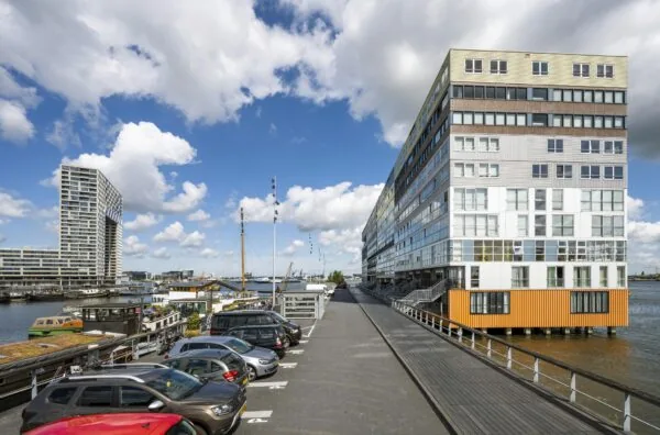 Moderne appartementencomplex Silodam in Amsterdam met uitzicht op het IJ en aangrenzende parkeergelegenheid.