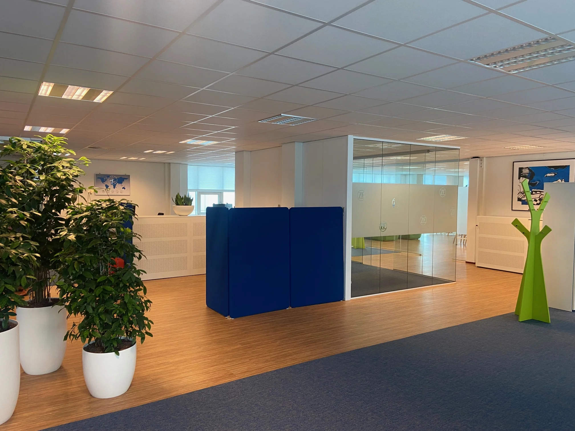 Moderne kantoorruimte in het Rhijnspoor-gebouw met glazen vergaderruimte, planten en kleurrijke decoratie.