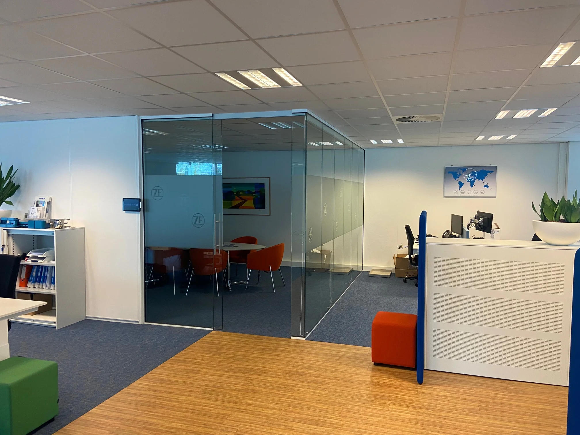 Moderne kantoorruimte in het Rhijnspoor-gebouw met glazen vergaderruimte, werkplekken en kleurrijke accenten.