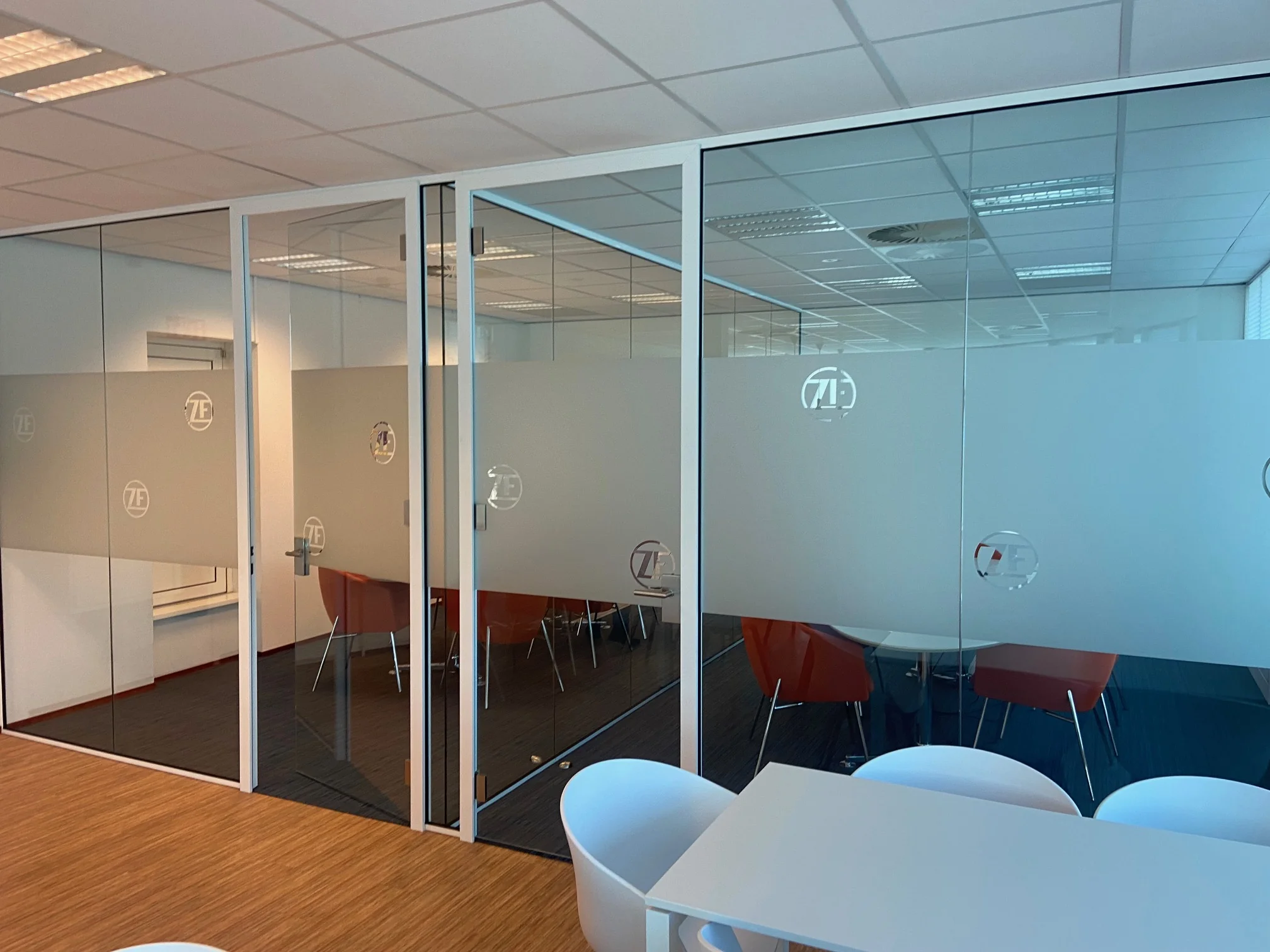 Vergaderruimte met glazen wanden en het logo van ZF bij het Rhijnspoor-kantoor.
