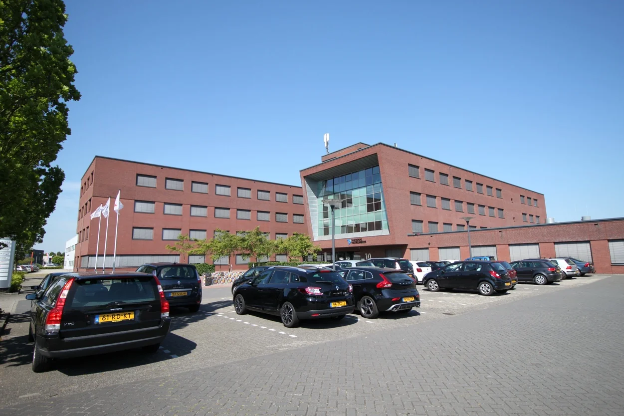 Modern rood bakstenen kantoorgebouw aan de Pompmolenlaan met parkeerplaatsen op de voorgrond.