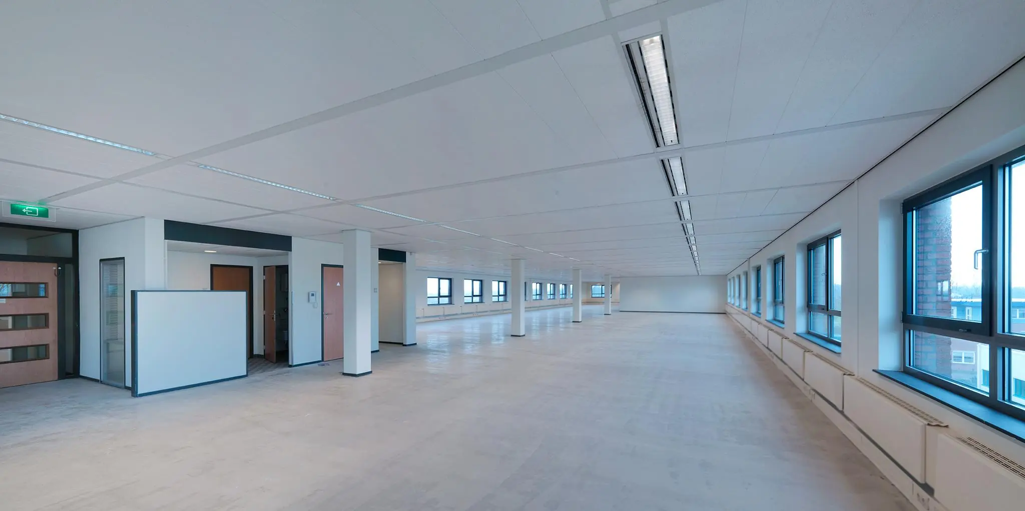 Lichte, lege kantoorruimte aan de Pompmolenlaan met grote ramen en systeemplafond.