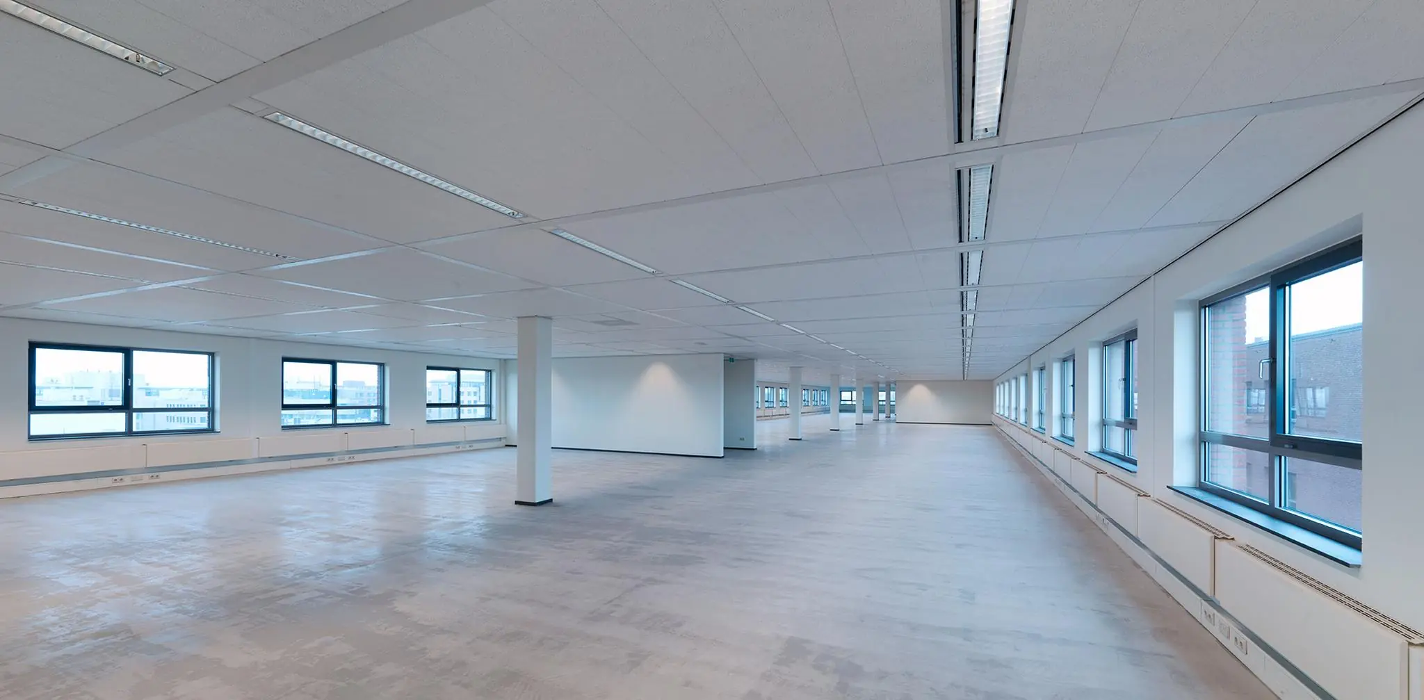 Leeg kantoorpand aan de Pompmolenlaan met grote ramen en systeemplafond.